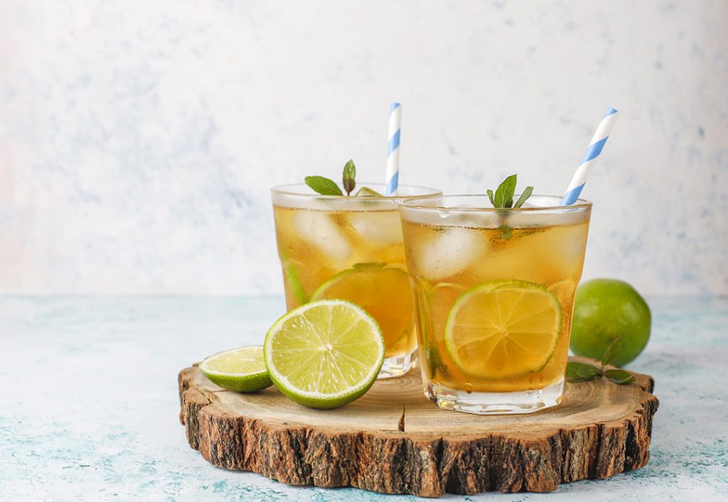 paper strawsIced tea with lime and ice on light background