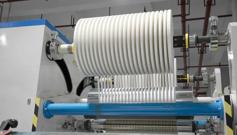 a jumbo roll of paper being slit into narrow strips for paper straw production