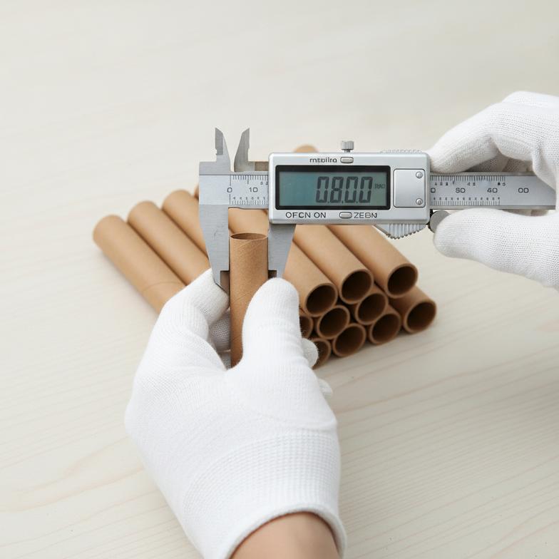 A quality control technician uses digital calipers to precisely measure the inner diameter of a firework paper tube.
