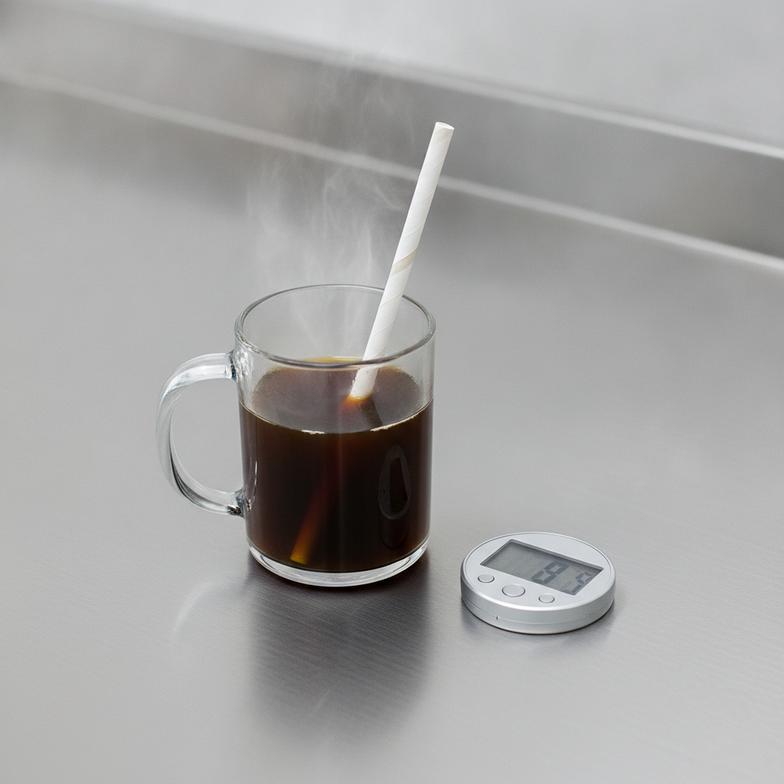 Testing the durability of a paper straw for hot drinks by timing it in a hot beverage.