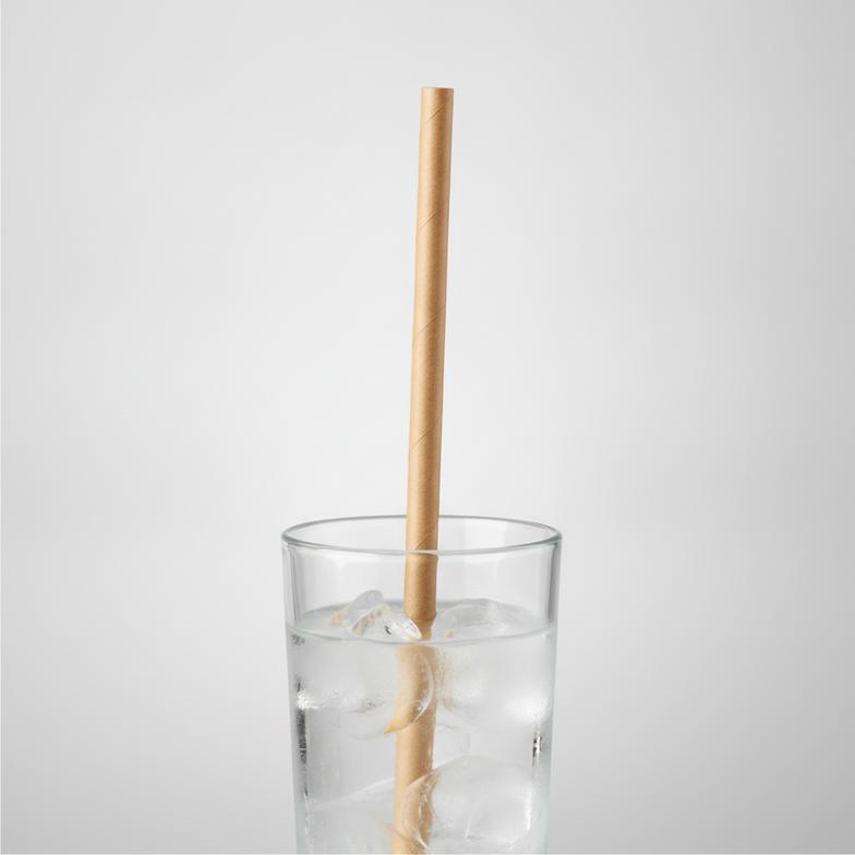 A person testing a paper straw's durability in a glass of iced coffee, a key part of a paper straw purchase specification.
